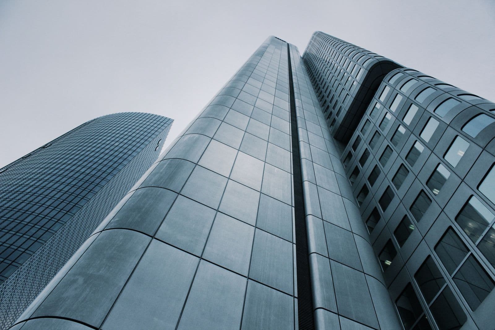 Cool-toned modern office towers seen from below — clean structural lines